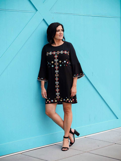  A woman models a black embroidered dress as an example of spring outfits for women.