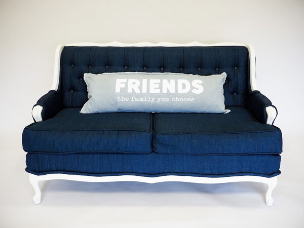 A rustic red and white blanket thrown over a modern, blue couch