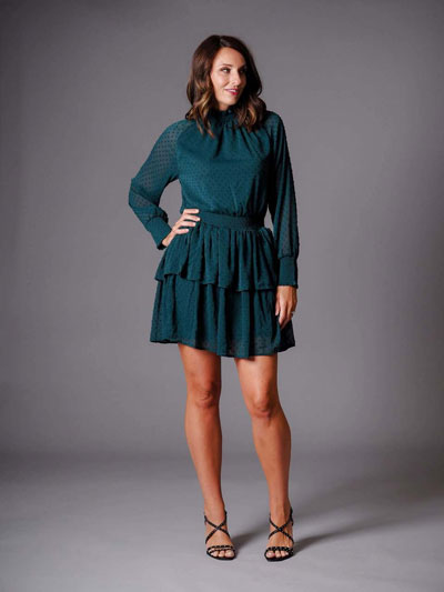 A woman models an emerald green, casual boutique dress