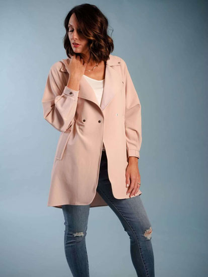 A woman models a cute Mother's Day outfit idea including a pale pink trench coat.