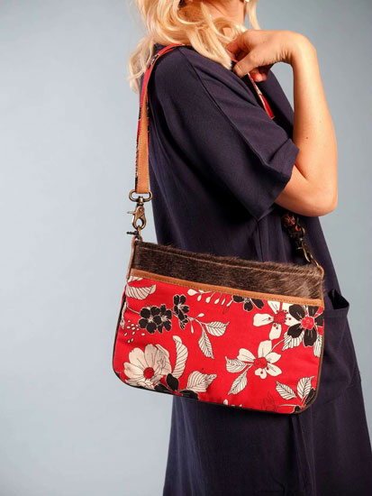 A woman models a cute Mother's Day outfit idea including a red, floral handbag.