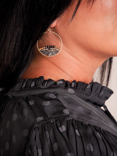Woman models beaded hoop earrings.