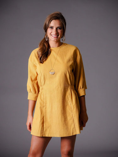 Woman models her autumn capsule wardrobe with a stylish yellow dress.