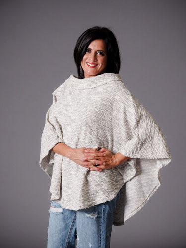 Woman flaunts her autumn capsule wardrobe with a stylish white poncho.