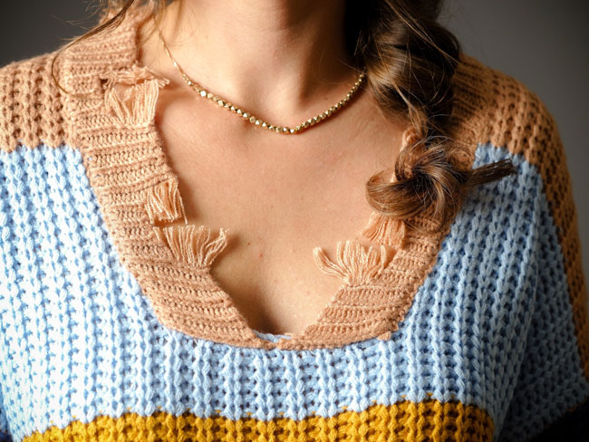 A woman models a dainty, gold necklace as a jewelry gift idea.