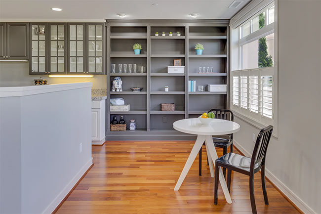 A gray painted shelving unit in a modern white kitchen