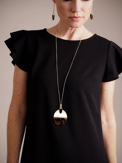 A woman models a long oval pendant necklace as an example of a unique Valentine's Day gifts.