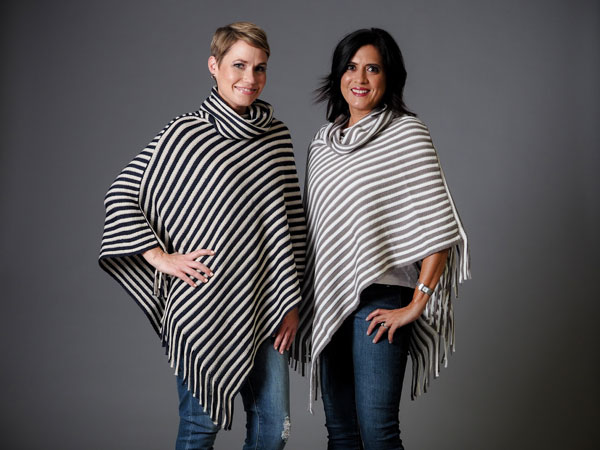 Two women model their cute, striped winter poncho sweaters. 