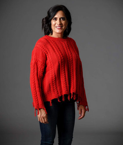 A woman models a cute, red cable knit sweater.