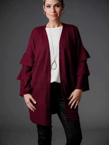 A woman models a ruffled red cardigan with a white shirt.