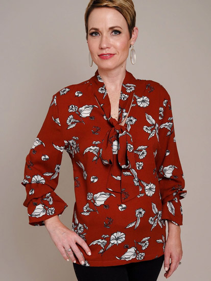 A woman models a floral, red spring boutique clothing tie-top.