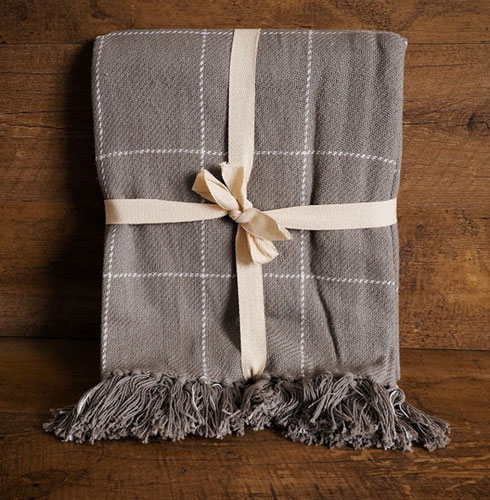 A gray, plaid throw blanket sits against a wooden background as an example of rustic farmhouse Christmas decor.