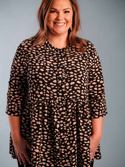 A woman models a black, spotted plus size boutique blouse.