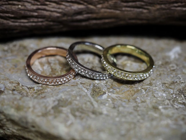 Three different colored rings sit on a stone surface.