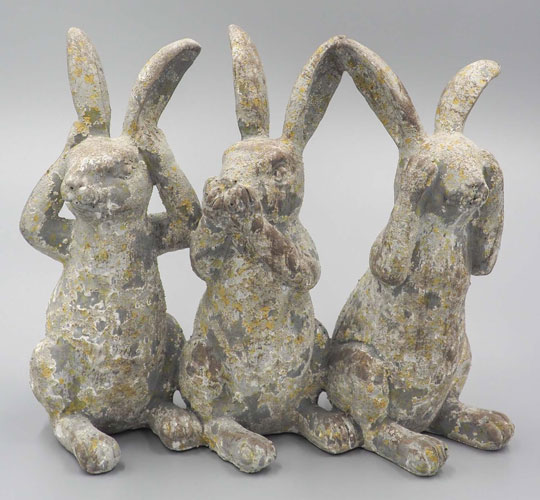 Three concrete rustic rabbit figurines sit in a line.