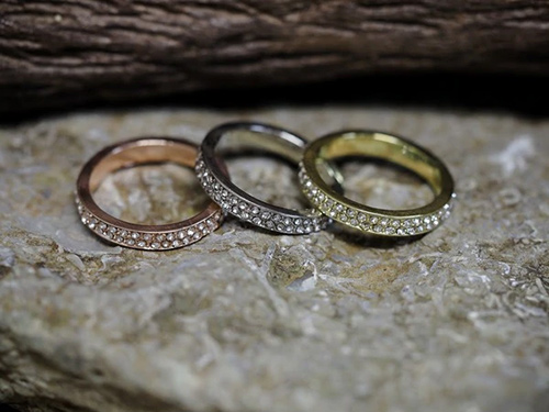 Three rings in gold, rose gold, and silver colors with glass stone embellishments.