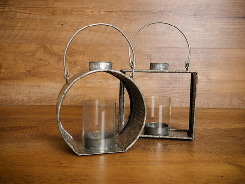 Two, rustic spring decor lanterns on a wooden surface.