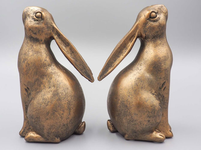 Two bronze rabbit rustic Easter decor centerpieces sit back back-to-back.