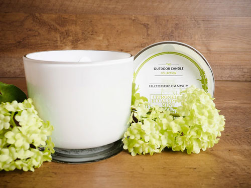 A white candle sits next to an arrangement of white hydrangeas