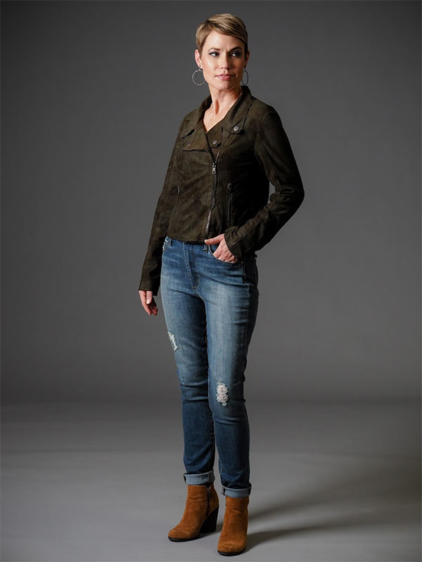 A woman models a brown, faux suede jacket and jeans as a casual holiday party outfit