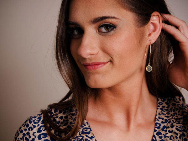 Woman models her long, dainty earrings. 