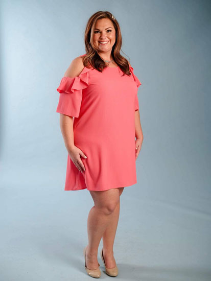 A woman models a ruffled sleeve plus size boutique dress in pink. 
