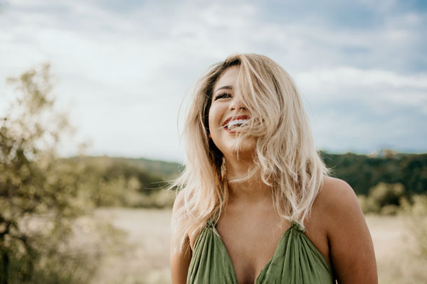 A woman standing in the desert laughs up at the sky.