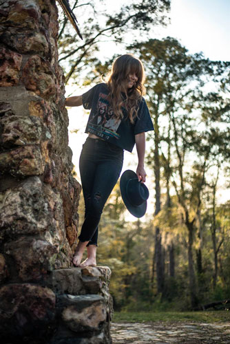 Woman posing near tree demonstrates how to style graphic tees with jeans.